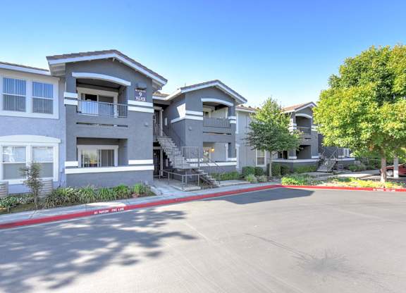 A sunny day at a residential complex with apartment buildings and a clear blue sky.
