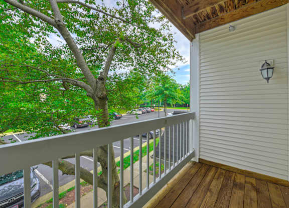 Covered balcony with wood deck and railing at Acclaim at Ashburn Apartments, Virginia