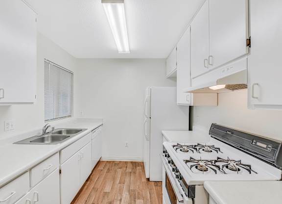 A white kitchen with a stove and sink.