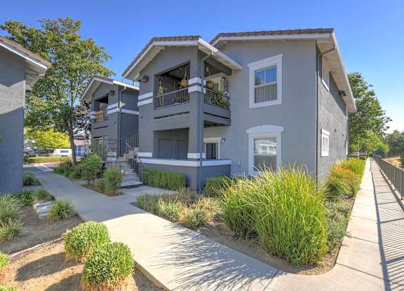 A modern two-story house with a balcony and a small garden in front.