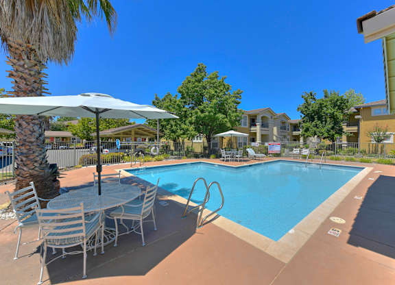 A pool with a table and chairs and a palm tree at Hurley Creek Apartment Homes, Sacramento, CA, 95834