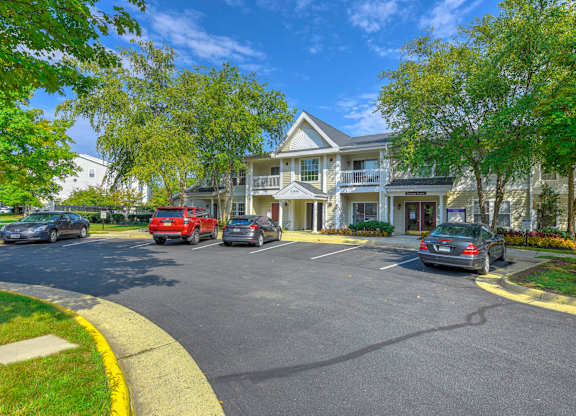 Parking area with apartment buildings and trees at Acclaim at Ashburn Apartments, Ashburn, VA