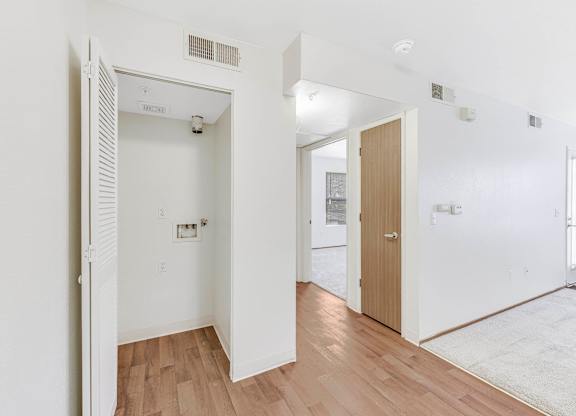 A white room with a wooden floor and a door on the left.