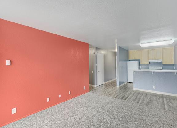 A room with a red wall and a kitchen area in the background at Oak Village Apartments, Oakland, 94607