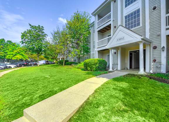 Apartment building exterior with landscaped walkway at Acclaim at Ashburn Apartments, Virginia, 20147