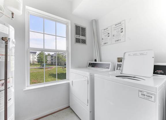 Laundry room with white washers and dryers at Acclaim at Ashburn Apartments, Ashburn, VA 20147