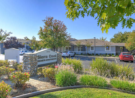 A sign for Sierra Creek Senior Apartments is in front of a building.