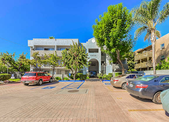 A parking lot with cars and a building in the background.
