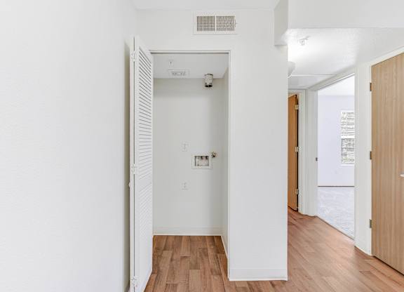 A white door is open to a room with wood flooring.