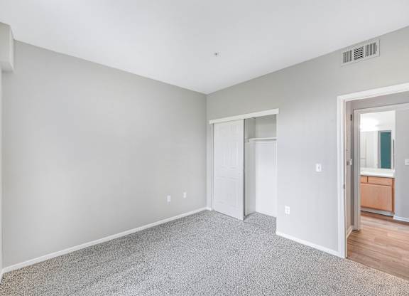 A spacious room with grey carpeting and white walls.