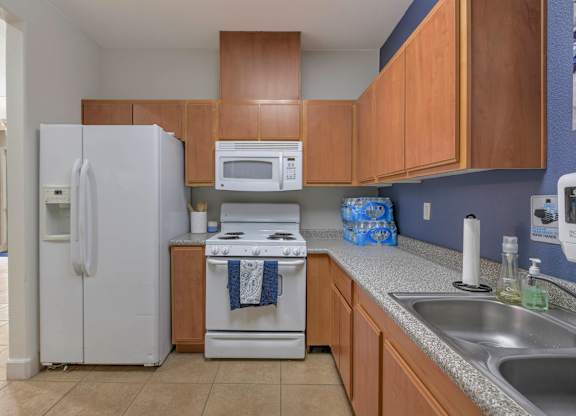 A kitchen with a white refrigerator, white stove, and a white microwave at Hurley Creek Apartment Homes, California, 95834