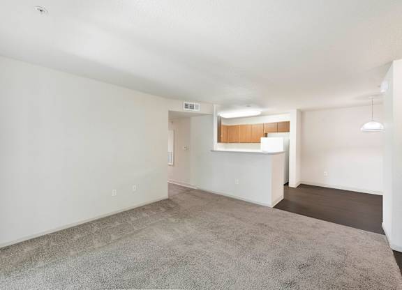 A large empty room with a grey carpet and white walls at Hurley Creek Apartment Homes, California