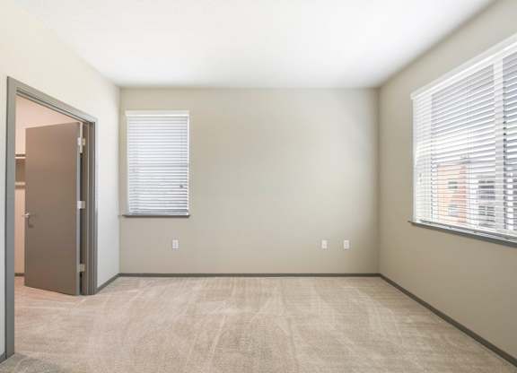 Empty bedroom with two windows and carpet flooring at Anton Arcade Apartments, Sacramento, California