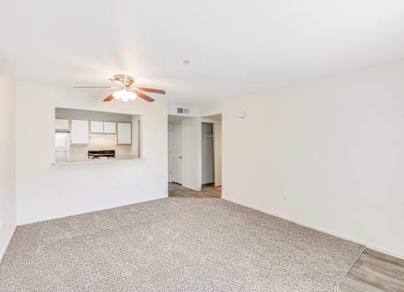 A spacious room with a ceiling fan and carpeted floor.