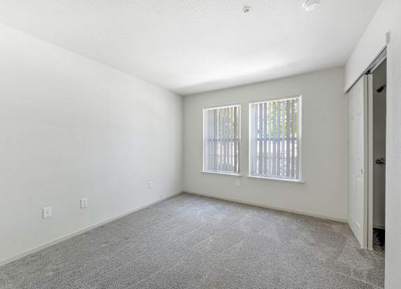 A room with a carpeted floor and a window with blinds at Hurley Creek Apartment Homes, California