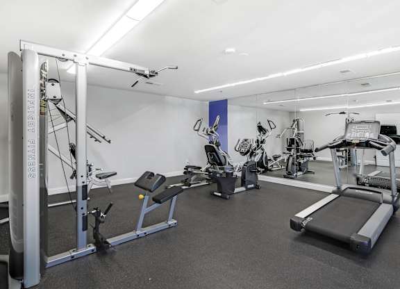 A gym with a variety of equipment including a treadmill, weights, and a bench press at Acclaim at Sterling, Sterling, VA