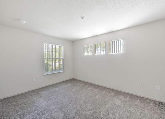 A spacious room with a carpeted floor and two windows at Hurley Creek Apartment Homes, Sacramento, 95834