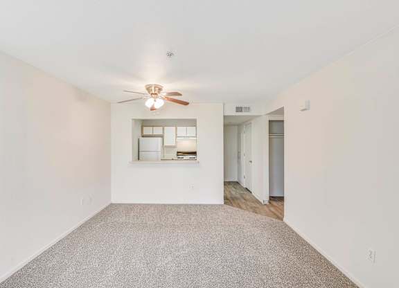 A spacious room with a ceiling fan and a carpeted floor.