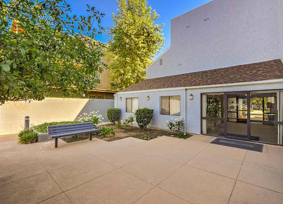 A white building with a bench in front of it.