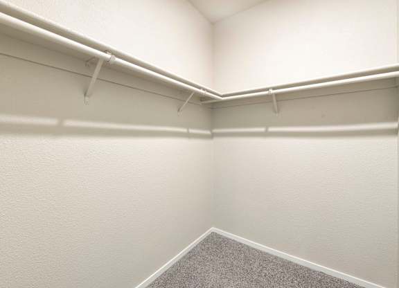 Walk-in closet with white shelving and carpet at Anton Arcade Apartments, California