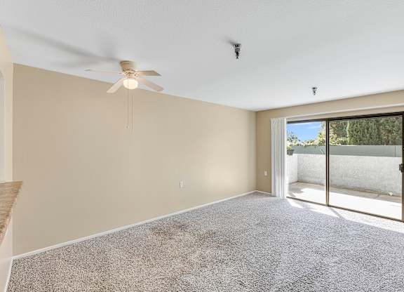 A room with a ceiling fan and carpeted floor.