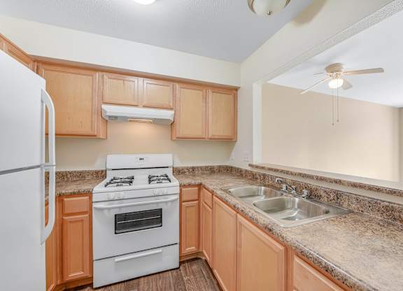 A kitchen with a white refrigerator, a white stove, and a granite countertop.