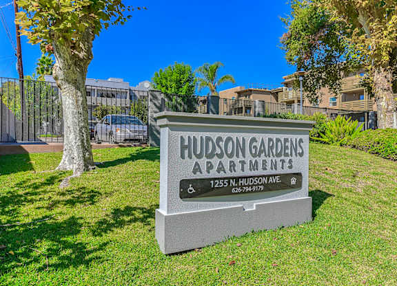 A sign for Hudson Gardens Apartments stands in a grassy area.