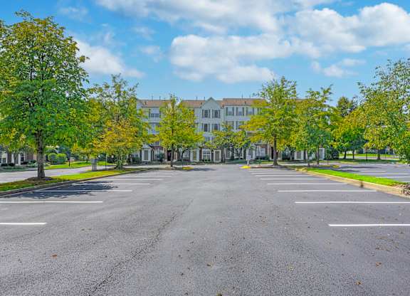 A parking lot with a building in the background and trees on the sides at Acclaim at Sterling, Sterling, VA 20164