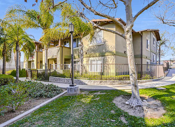 A tree in front of a building with a fence around it at Yorba Linda Apartments, California