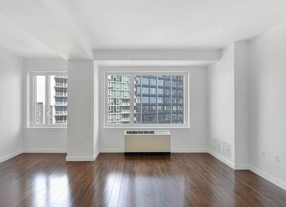 A large empty room with a window and a wooden floor. at 7 Dekalb, Brooklyn, New York