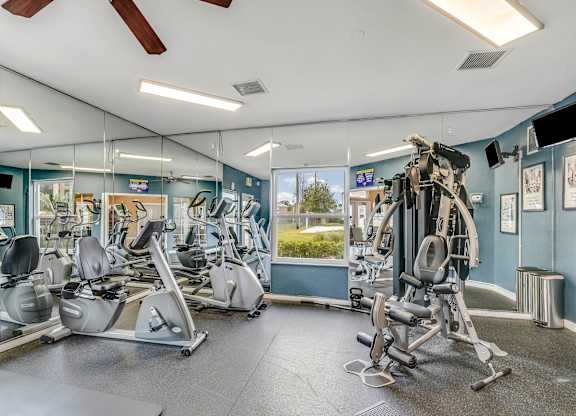 A gym with a variety of exercise equipment including treadmills, stationary bikes, and weight machines.