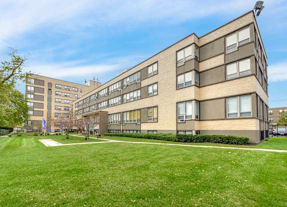 A large building with a green lawn in front. at Academy at Drexel Apartments, Chicago, IL