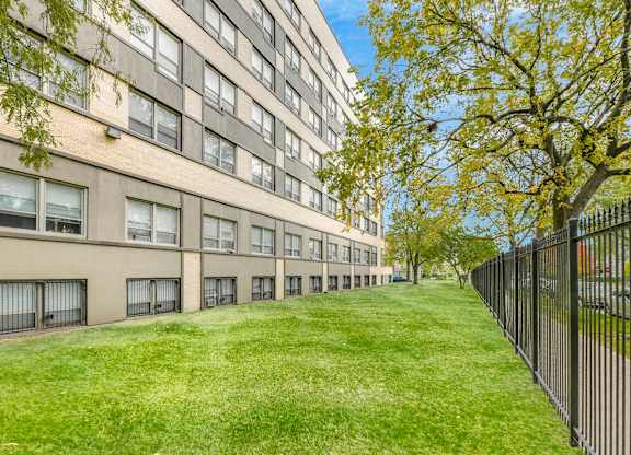 A long building with a fence on the right side. at Academy at Drexel Apartments, Chicago, Illinois