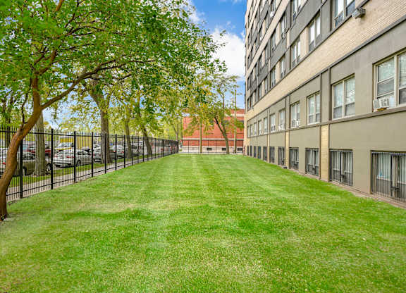 A long grassy area in front of a building. at Academy at Drexel Apartments, Chicago, IL, 60637