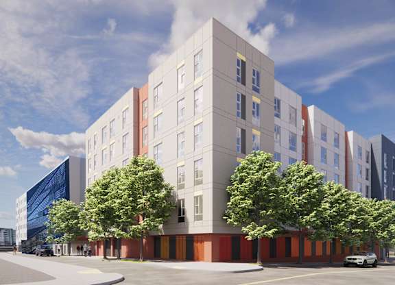 A modern building with a red and white facade is surrounded by trees and has a clear blue sky above at Elora Apartments, El Cerrito, CA 94530