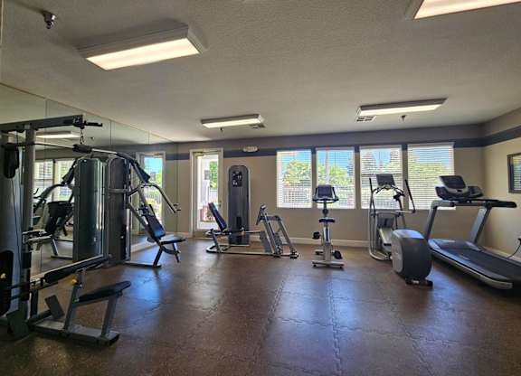 A gym with a variety of equipment including treadmills, weights, and exercise machines.