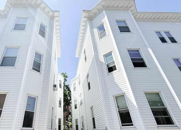 A white building with multiple windows is seen from below.