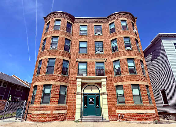 A red brick building with a green door in front.
