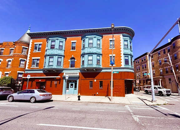 A street view of a red and blue building with cars parked in front.