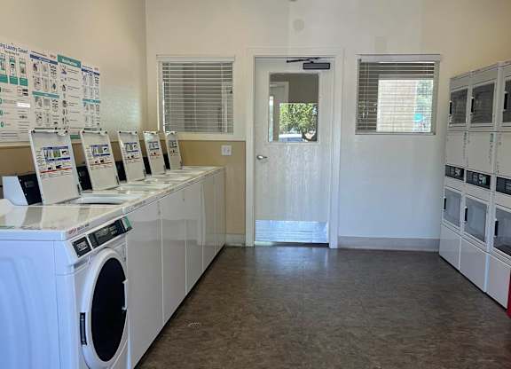 A laundromat with washers and dryers lined up.