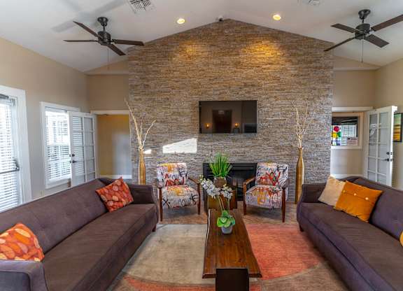 A community lounge room with a stone fireplace and a television above it.at Retreat at Valencia Apartment Homes, Orlando, 32825