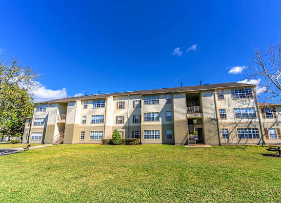 A large apartment building with a grassy area in front at Retreat at Valencia Apartment Homes, Orlando Florida