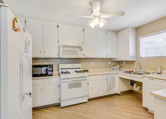 A kitchen with white appliances and cabinets.