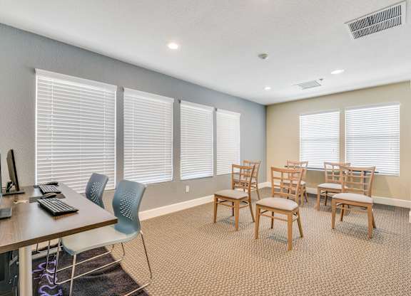 A room with a desk, chairs, and windows.