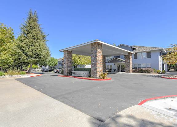A building with a sign that reads "Butter Terrace" is surrounded by trees and a parking lot.