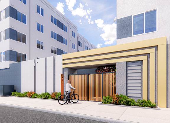 A person is riding a bicycle in front of a building at Rivo Apartments, California