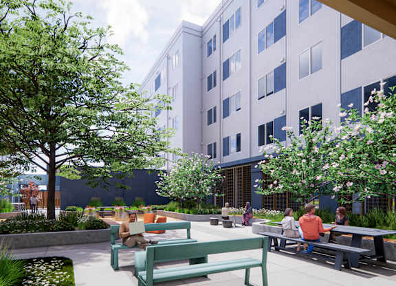 A park with people sitting on benches and a tree in the foreground at Rivo Apartments, Sacramento, CA