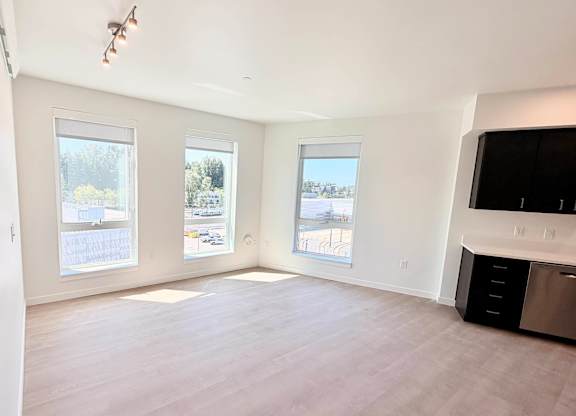 A spacious room with a large window overlooking a parking lot.