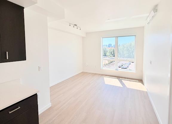 A spacious room with a large window overlooking a parking lot.