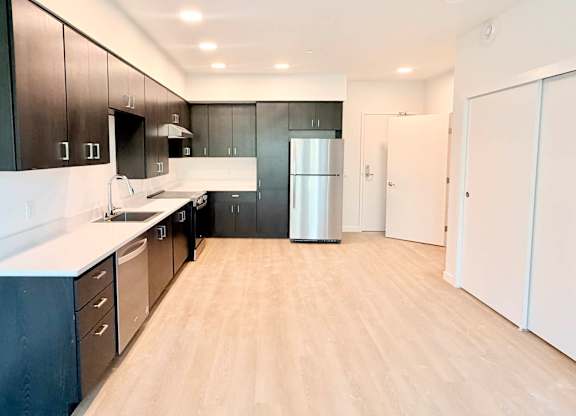 A kitchen with black cabinets and a white refrigerator.